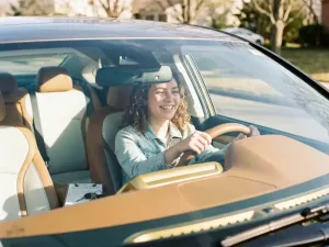 Junger Erwachsener am Steuer eines modernen Autos mit Fahrschul-Checkliste und Schlüsseln auf dem Armaturenbrett, warmes Morgenlicht.